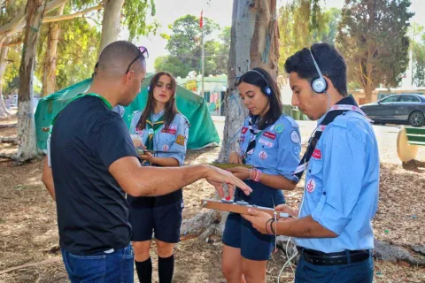 Tunisian Scouts stand in a circle at camp with headphones on while participating in JOTA-JOTI activities 2023