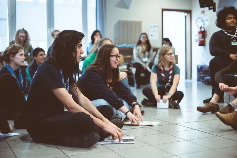 A group of young people sit on the floor.