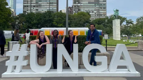 Three Youth Representatives and the Secretary General of WOSM pose behind a #UNGA sign