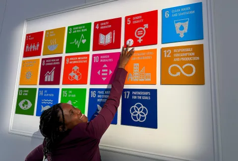 Ivy Murugi, a WOSM Youth Representative, points to an SDG 4 sign for Quality Education at the United Nations headquarters