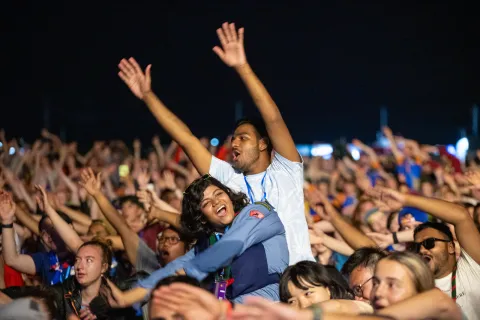 Two Scouts stand out from a huge crowd of Scouts, waving their arms in the air
