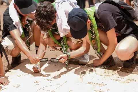 Scouts pintando con lupas y luz solar.