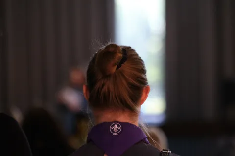A woman with her hair up wears a purple Scout scarf.