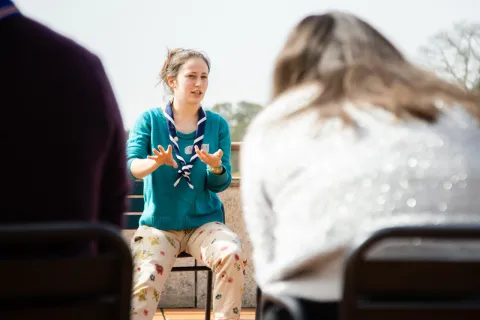 Raluca wears the Romanian Scout scarf and speaks in front of participants during a training on gender equality.