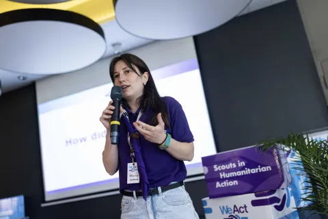 Raluca holds a microphone and presents during the WeAct Forum.