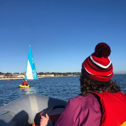 A woman in a boat and a second boat sailing in the front.