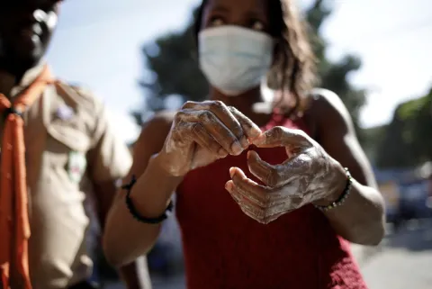 Woman wears mask as she washes hands with soap