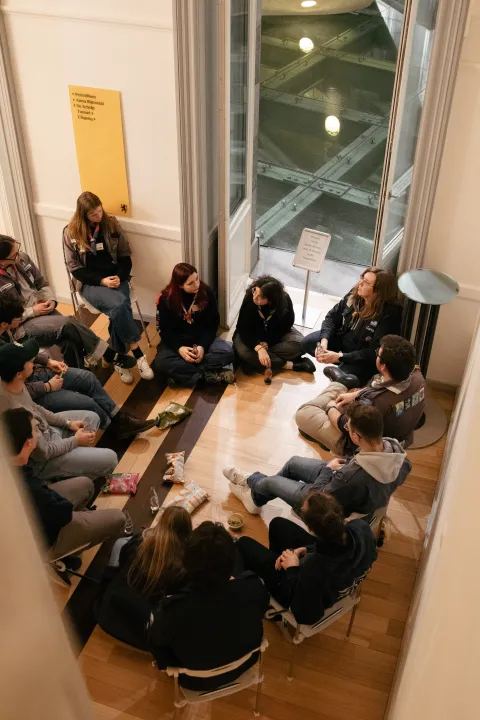 Young people sit on the floor making a circle.