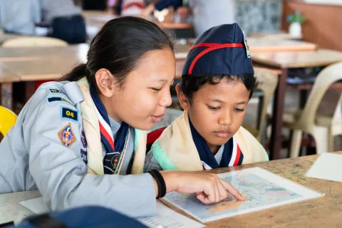 A young girl explaining a picture to a younger boy during JOTA-JOTI