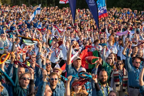 Participants at Roverway 2024 chear and hold their scarves in the air.
