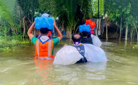 Scouts carrying belonging through flood waters