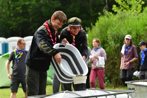 Two Polish Scouts pour a bucket into another container