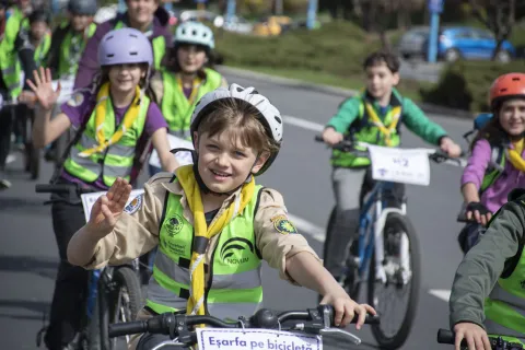 A young Scout makes the Scout salute while riding a bike.