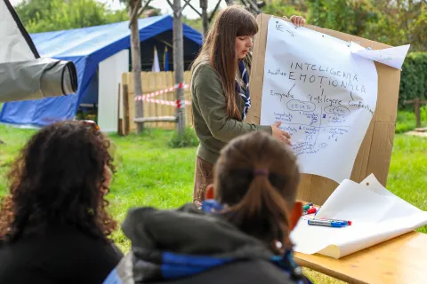 A facilitator points at a flipchart while participants look at it.