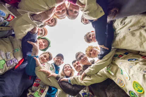 Scouts of different ages intertwin arms in a circle.