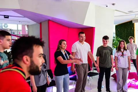 Young people stand next to each other smiling and moving.