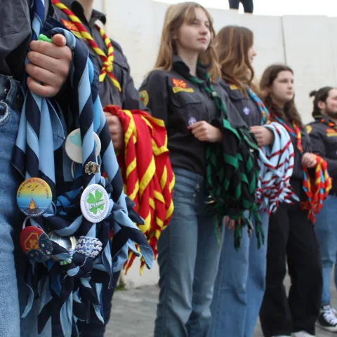 A group of Scouts stand next to each other holding scarves.