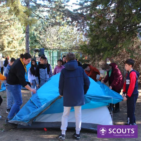 A group of Scouts standing around a blue and white tent.