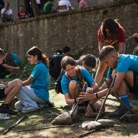 four young people create small constructions with sticks and ropes.