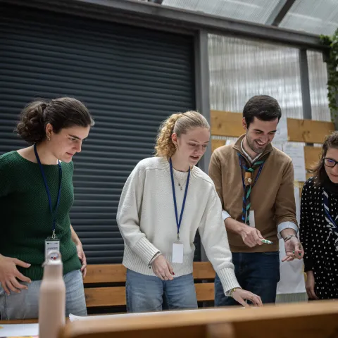 Young people standing in front of a table and placing sticky notes.